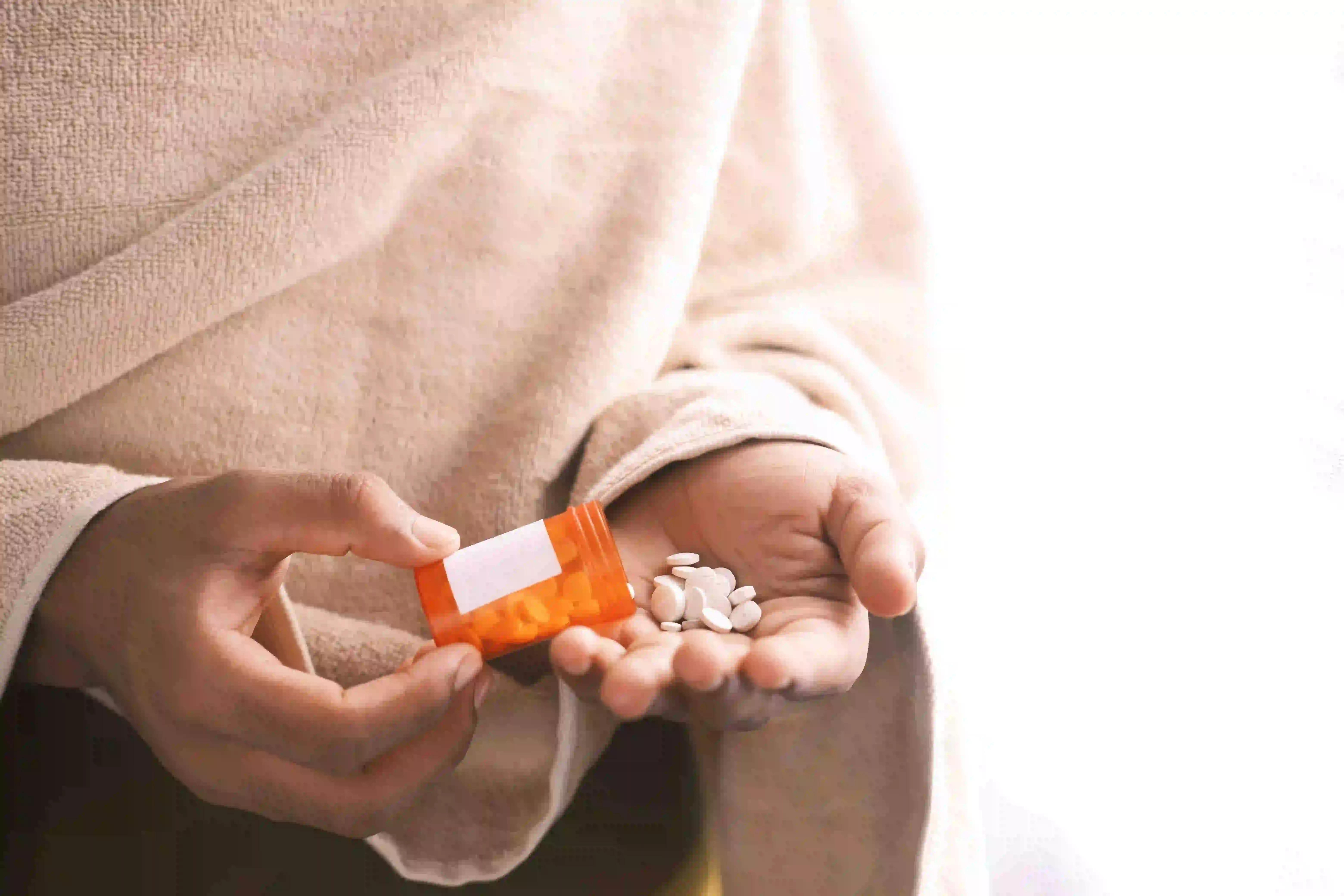 Eine Patientin schüttet Tabletten aus einem Tablettenbehältnis in ihre Hand.