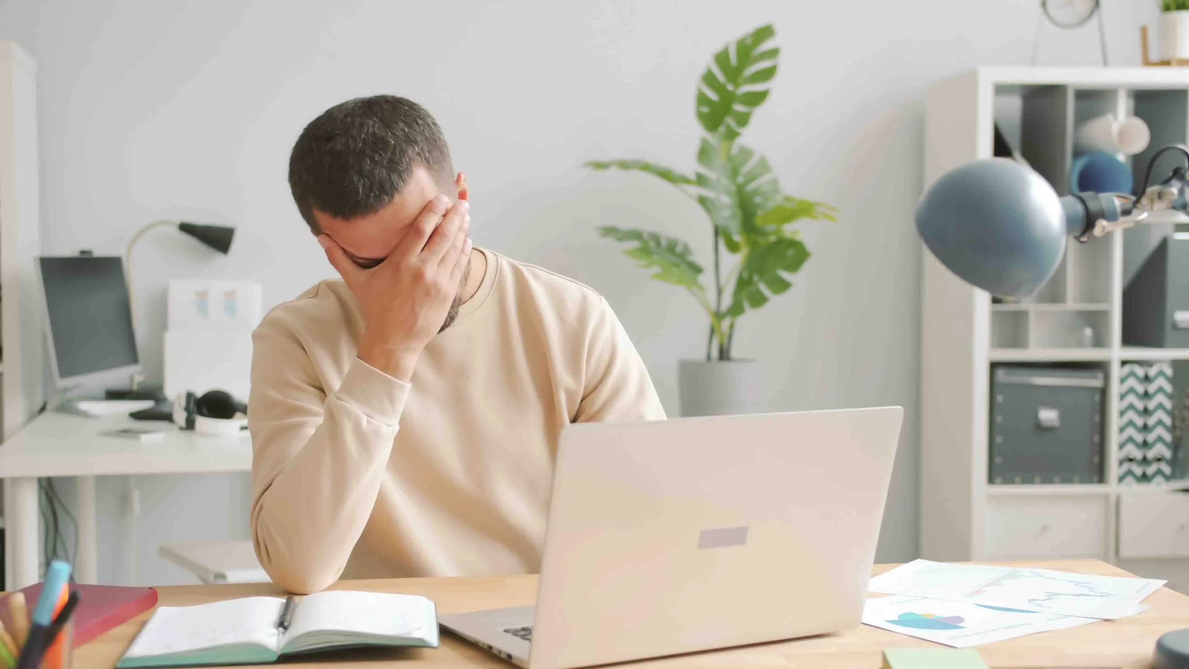 Ein Mann im öffentlichen Dienst mit Burnout reibt sich das Gesicht vor dem Laptop.