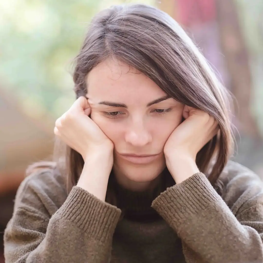 Eine Lehrerin mit Depressionen stützt den Kopf in ihre Hände.