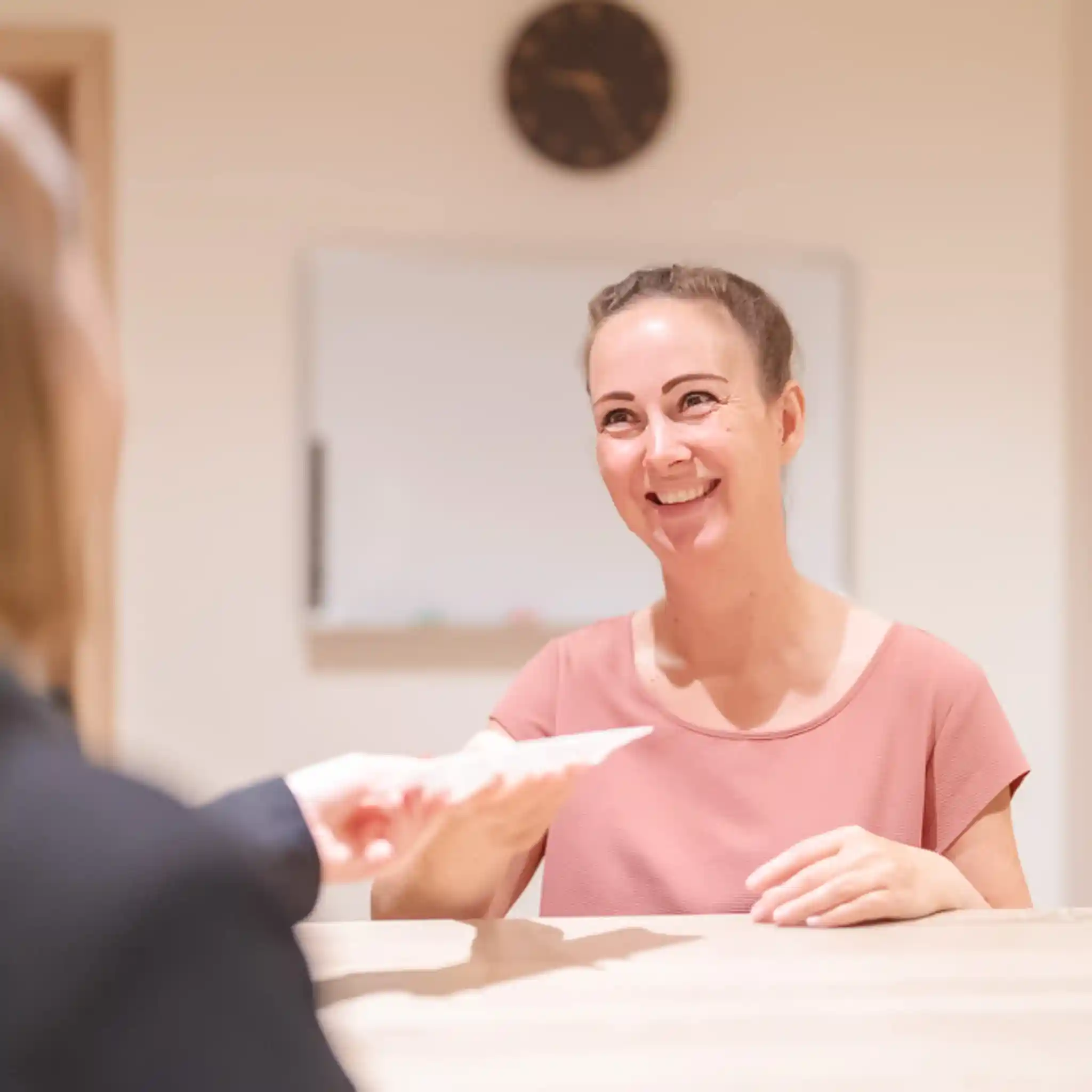 Eine Patientenmanagerin übergibt Unterlagen an eine Patientin.