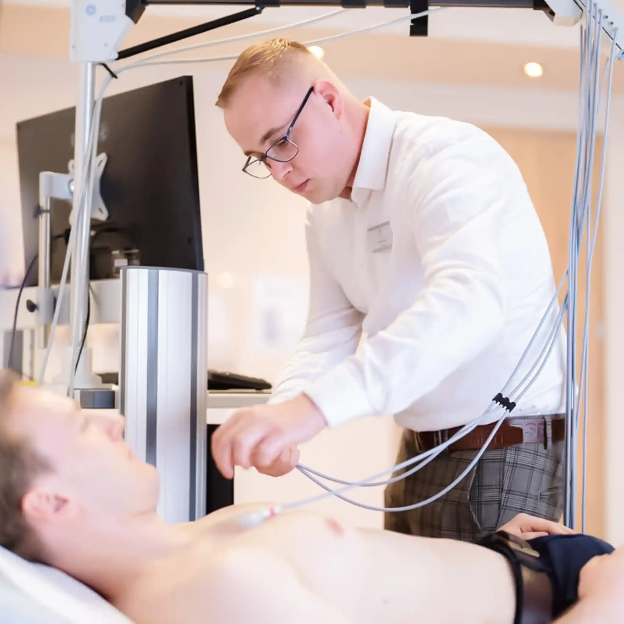 Ein Mitarbeiter legt Elektroden an einem Patienten an 