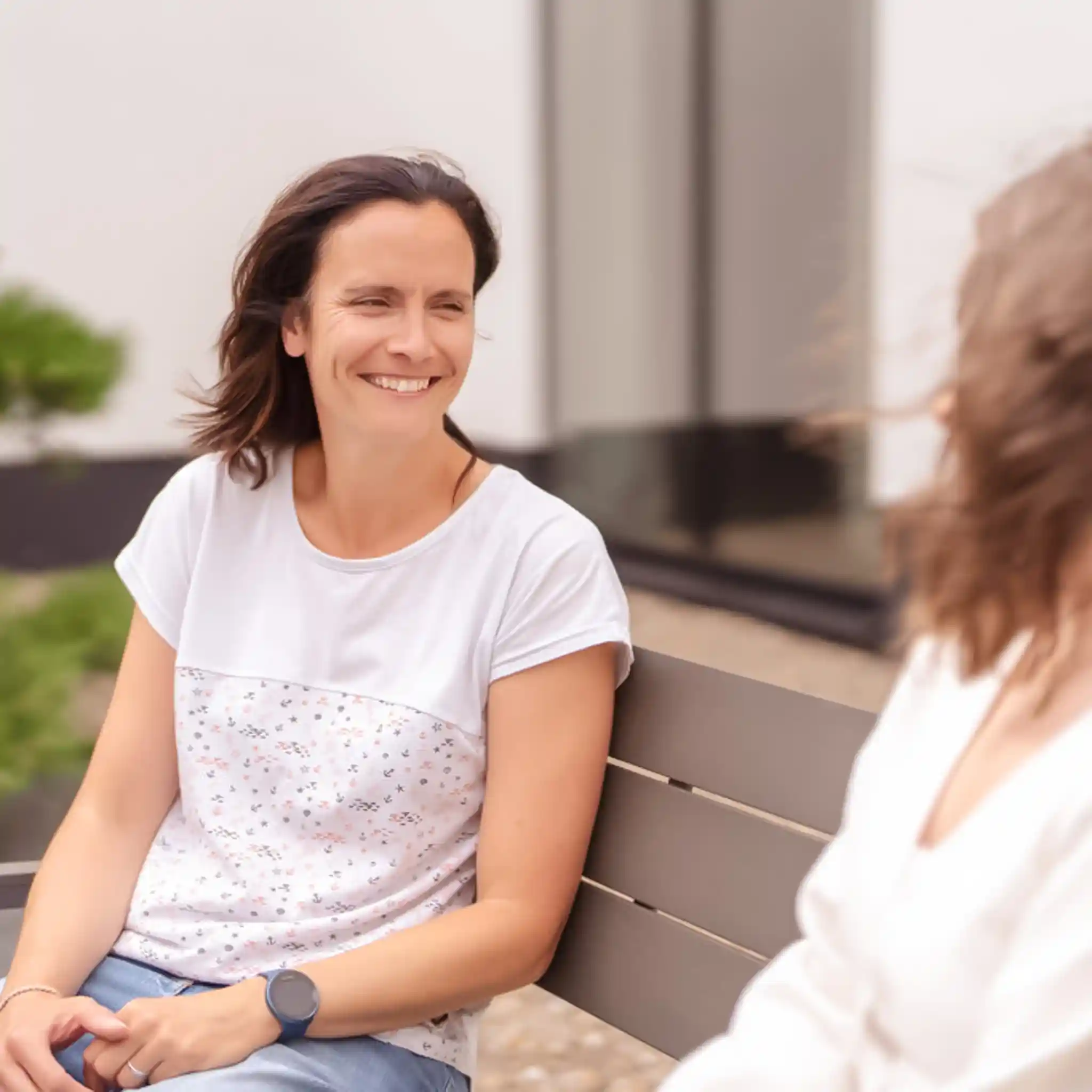 Zwei Frauen sitzen auf einer Bank und unterhalten sich