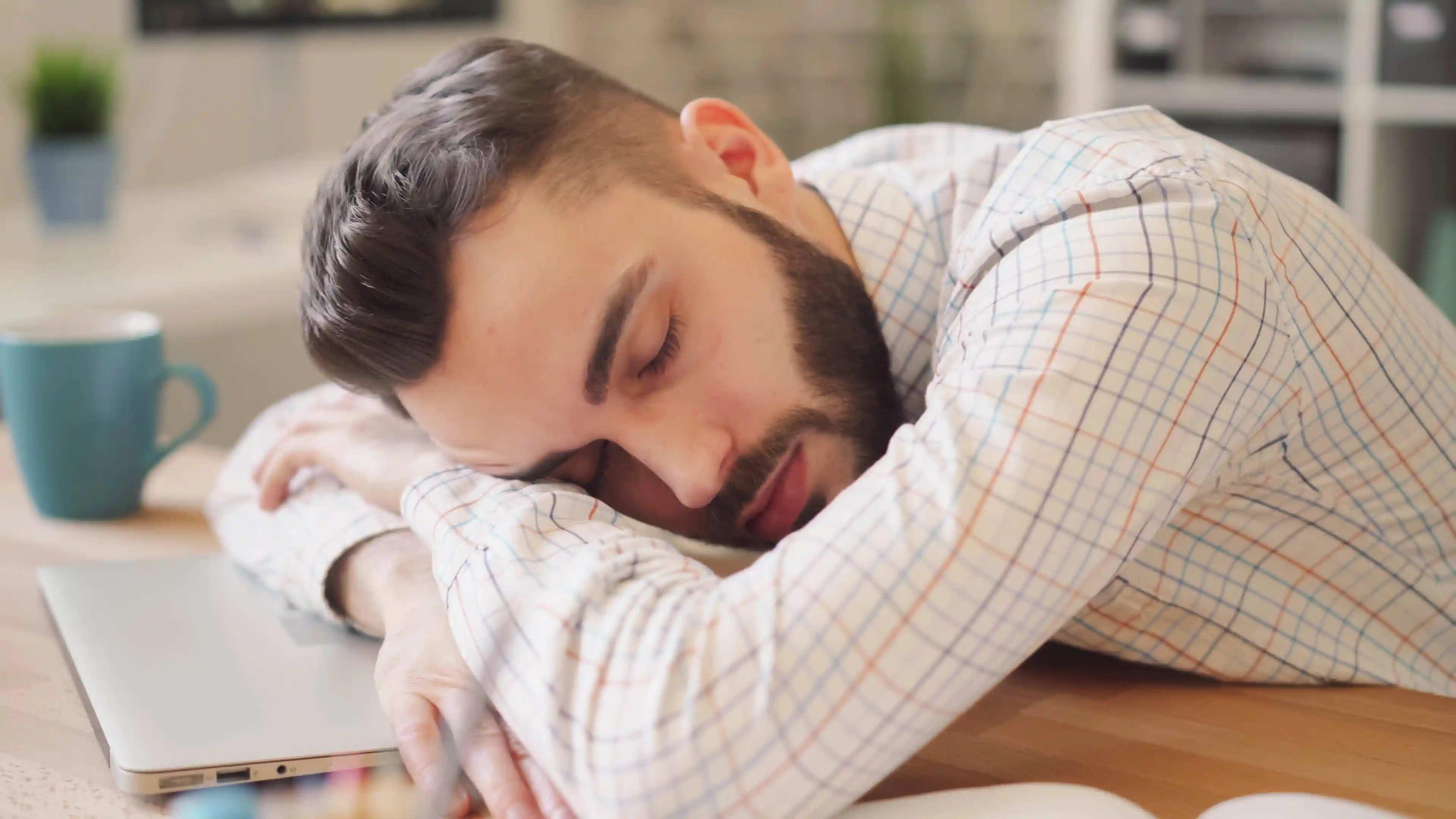 Ein Mann liegt schlafend auf mit verschränkten Armen auf dem Tisch