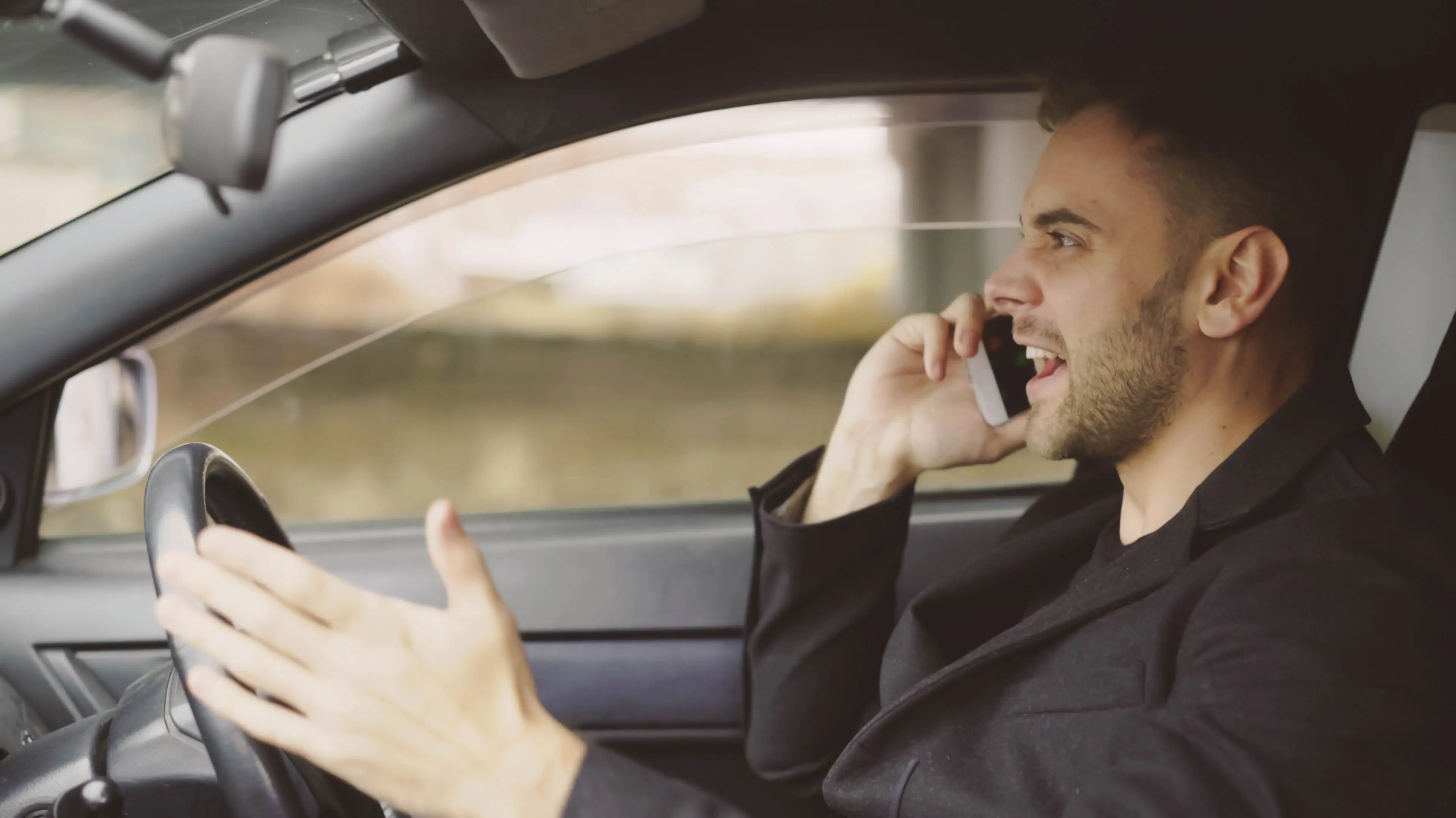 Ein Mann telefoniert bei Autofahren und schreit