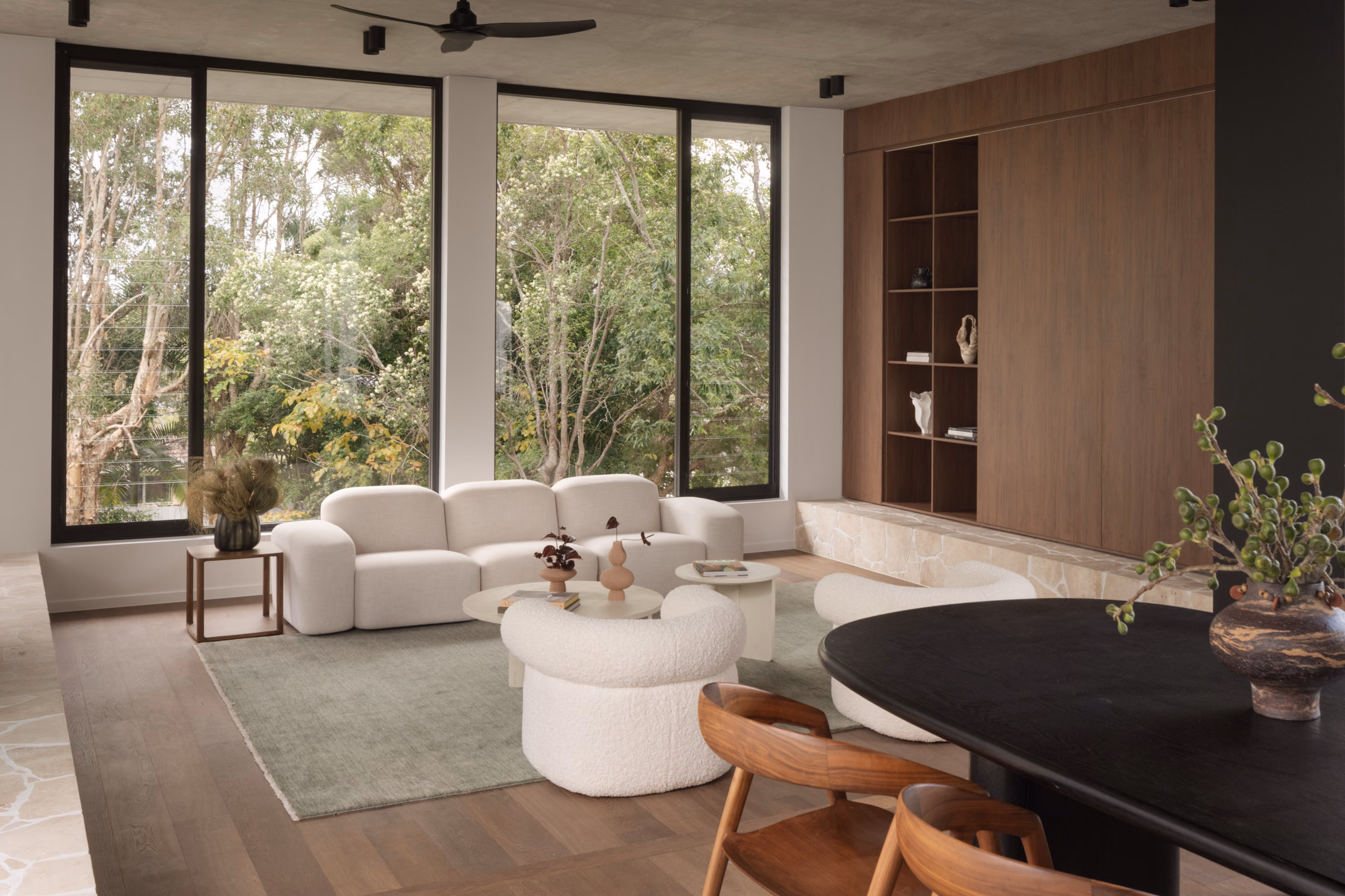 Stanley living room with curved white seating, stone fireplace, oversized windows, and a soft neutral palette overlooking the courtyard.