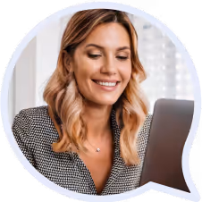 Uśmiechnięta kobieta z jasnobrązowymi włosami patrząca na ekran laptopa.