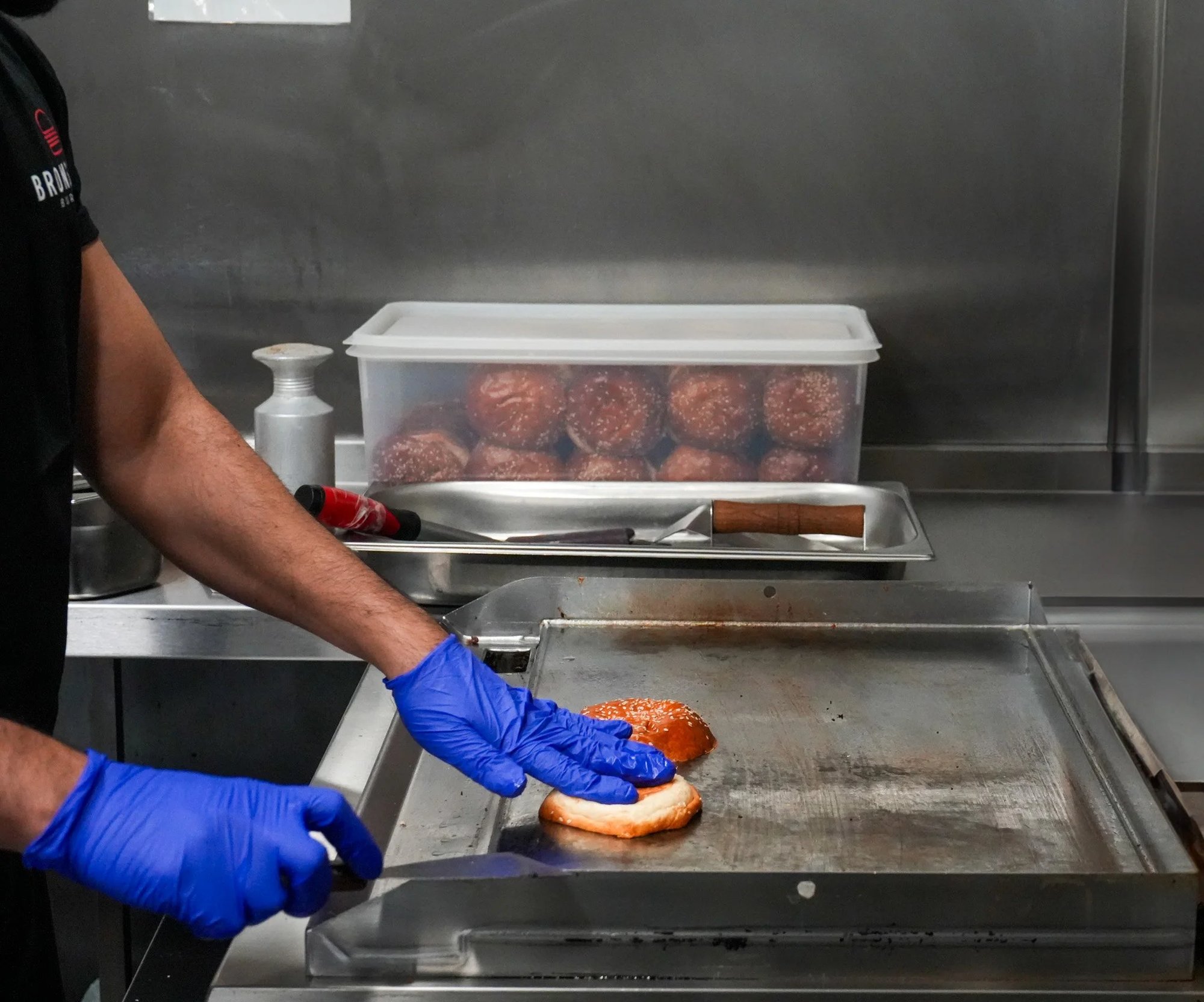 Burgers being cooked on a grill in an Encore kitchen