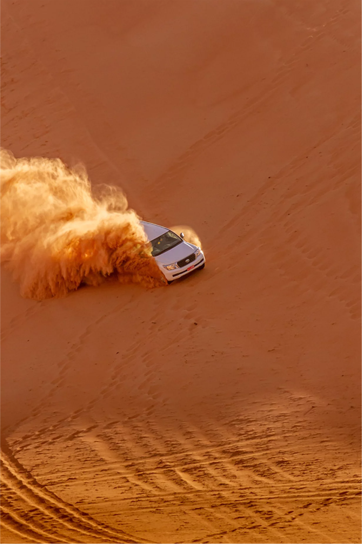 Geländewagen fährt durch die roten Dünen der Wahiba Sands im Oman