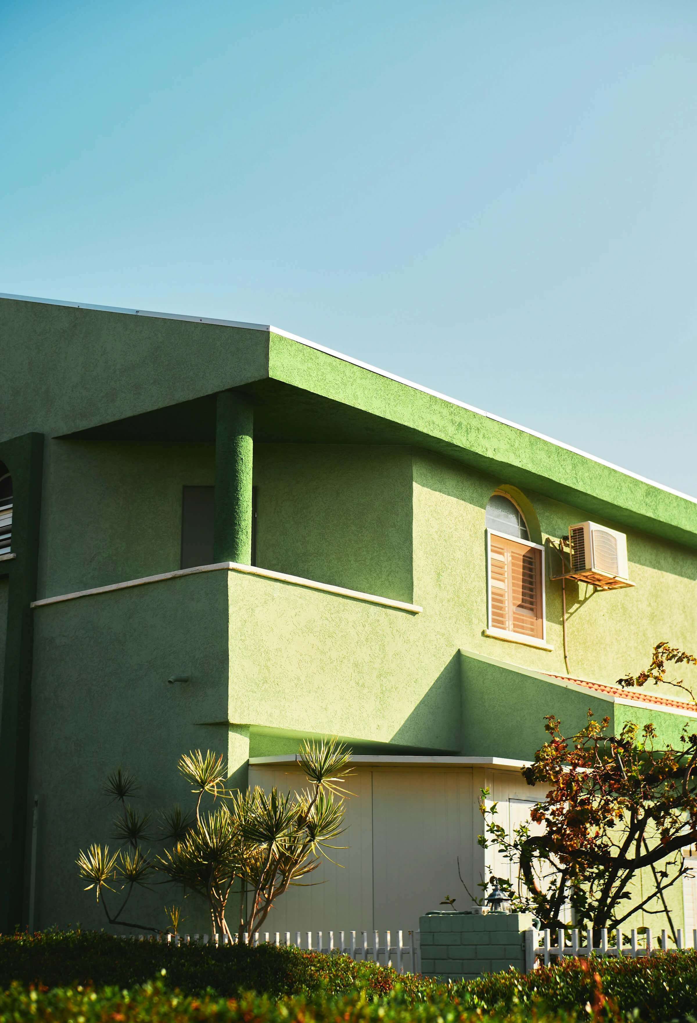 A green house featuring a prominent clock on its exterior, blending nature with timekeeping elements.