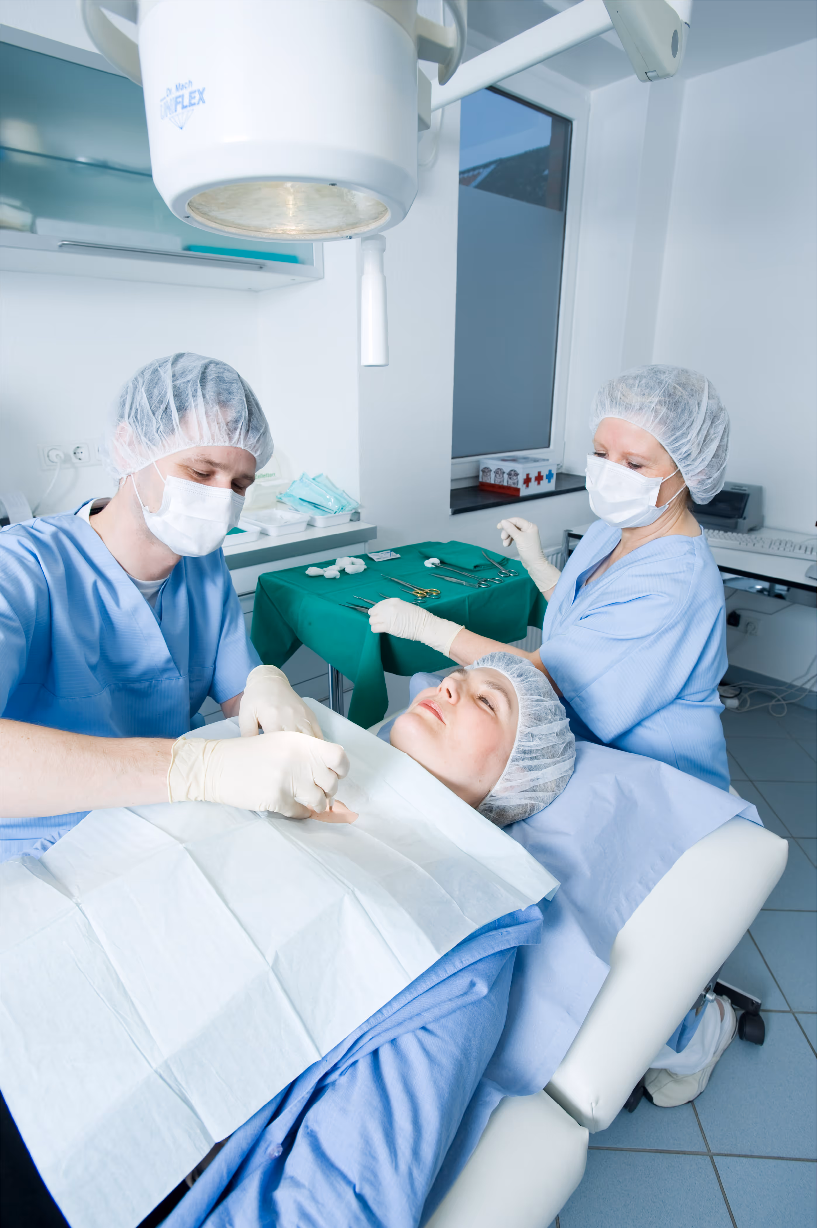 Ein Arzt mit einer medizinischen Fachangestellten operieren in einem sterilen Raum eine Patientin