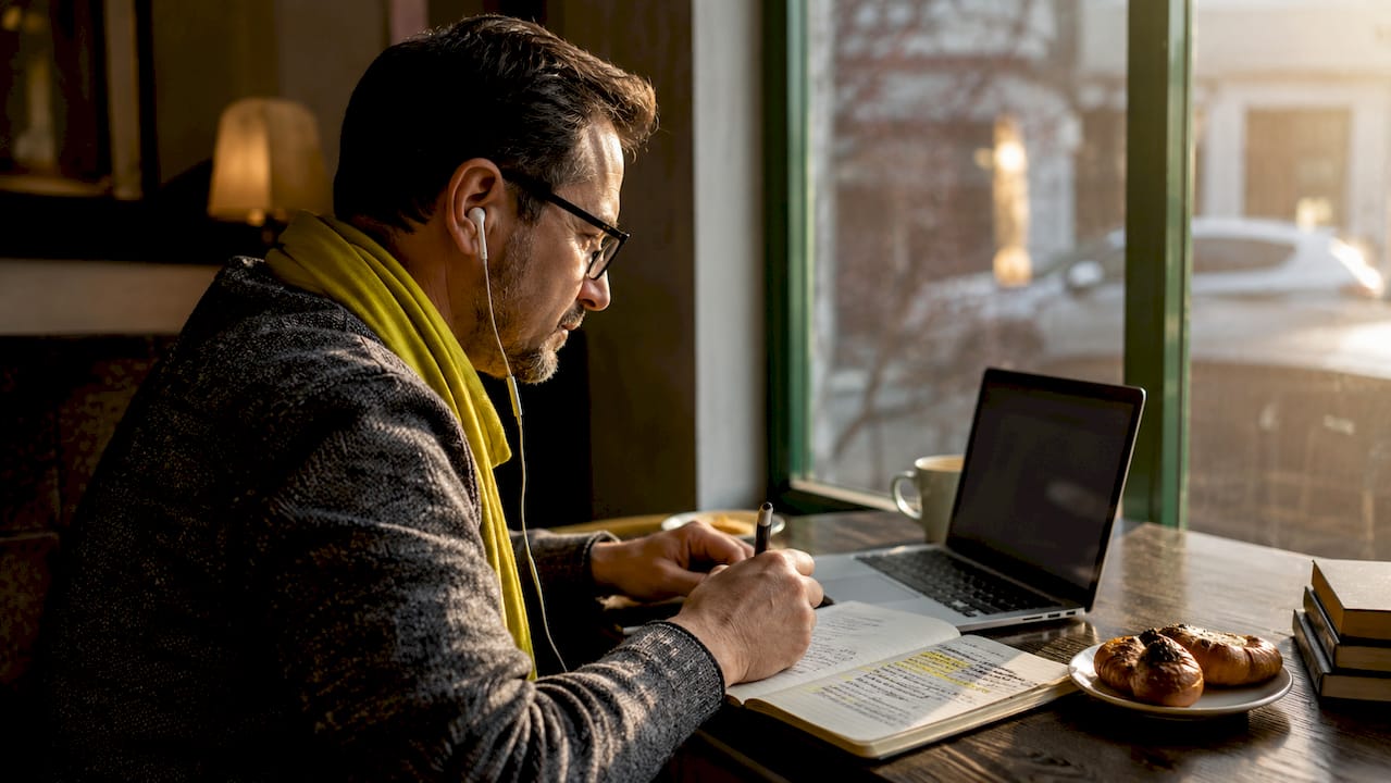 Man actively studying language playlist notes in library