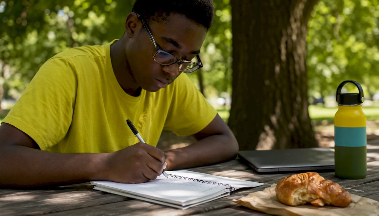 Teen writing vocabulary sentences in cafe