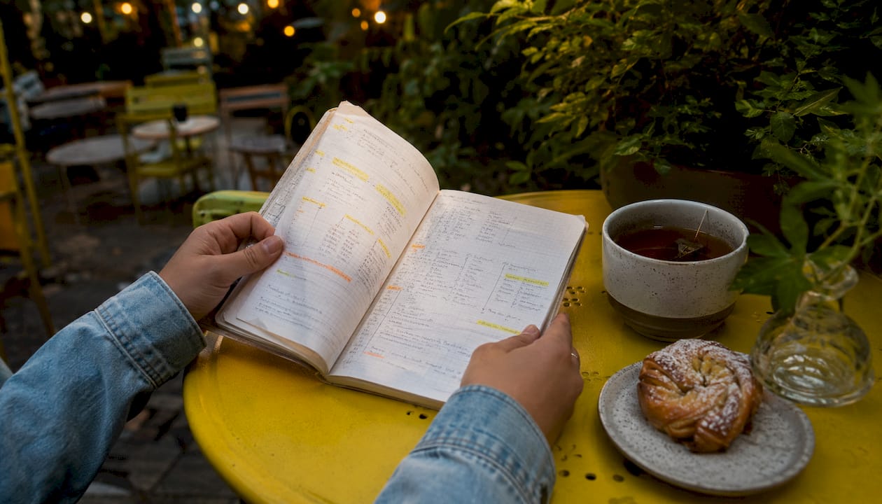 Hands studying French verb patterns in notebook