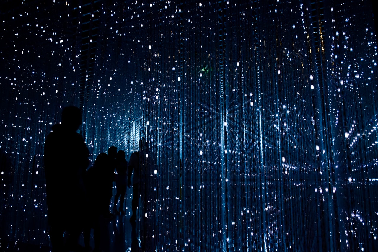 Silhouettes observe sparkling blue digital light installation