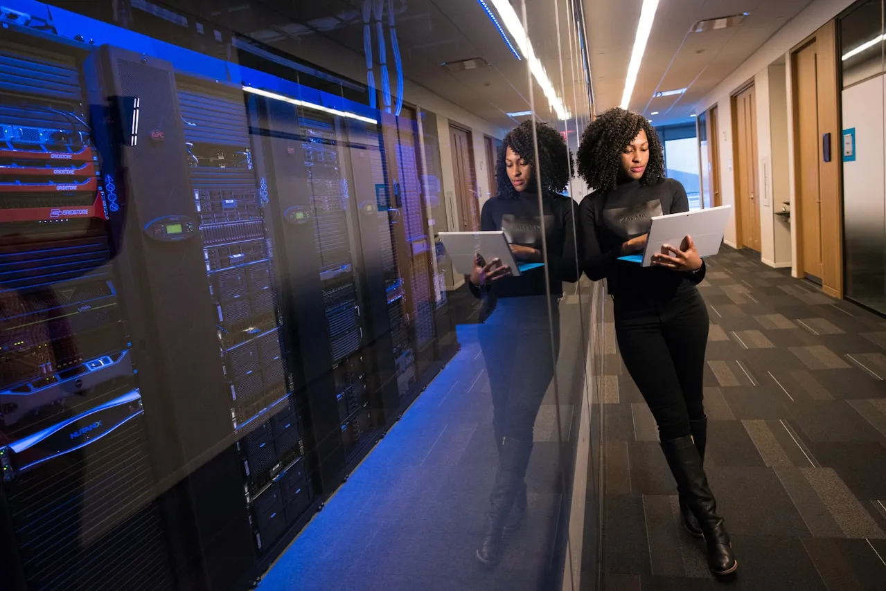 Technical professional working in server room with laptop and blue lighting