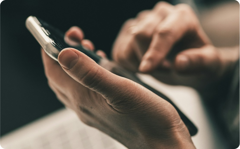 Close-up of hands holding and using a smartphone with blurred background
