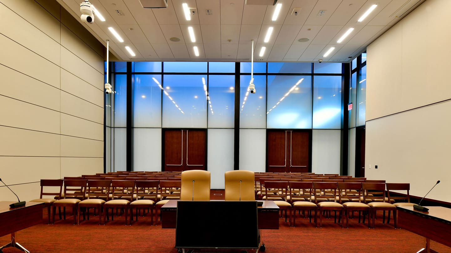 An interior photo of an assembly room with a semi-translucent glass curtain wall.
