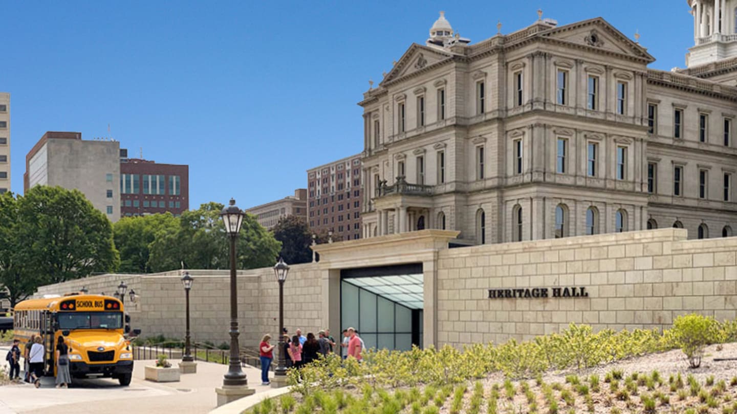 An exterior photo of a school bus and a group of people outside the entrance to Heritage Hall.