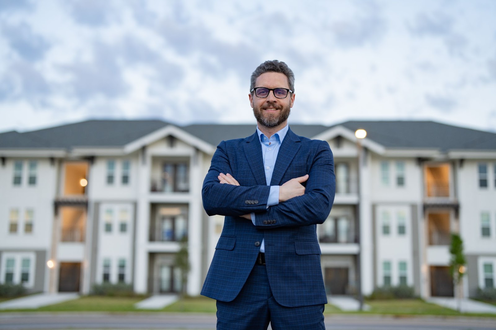 a happy local real estate agent standing in front of a condo complex