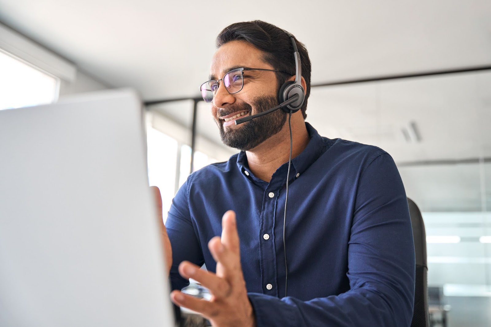 A smiling middle-aged real estate agent wearing a headset and talking to a seller