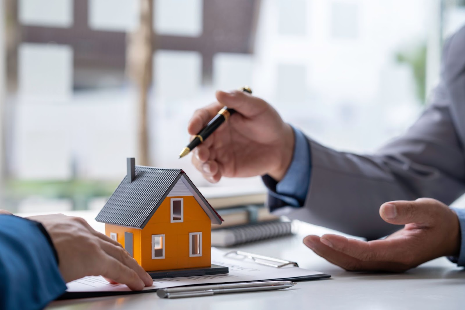 An absentee owner talking to a real estate agent with a close-up on a house model