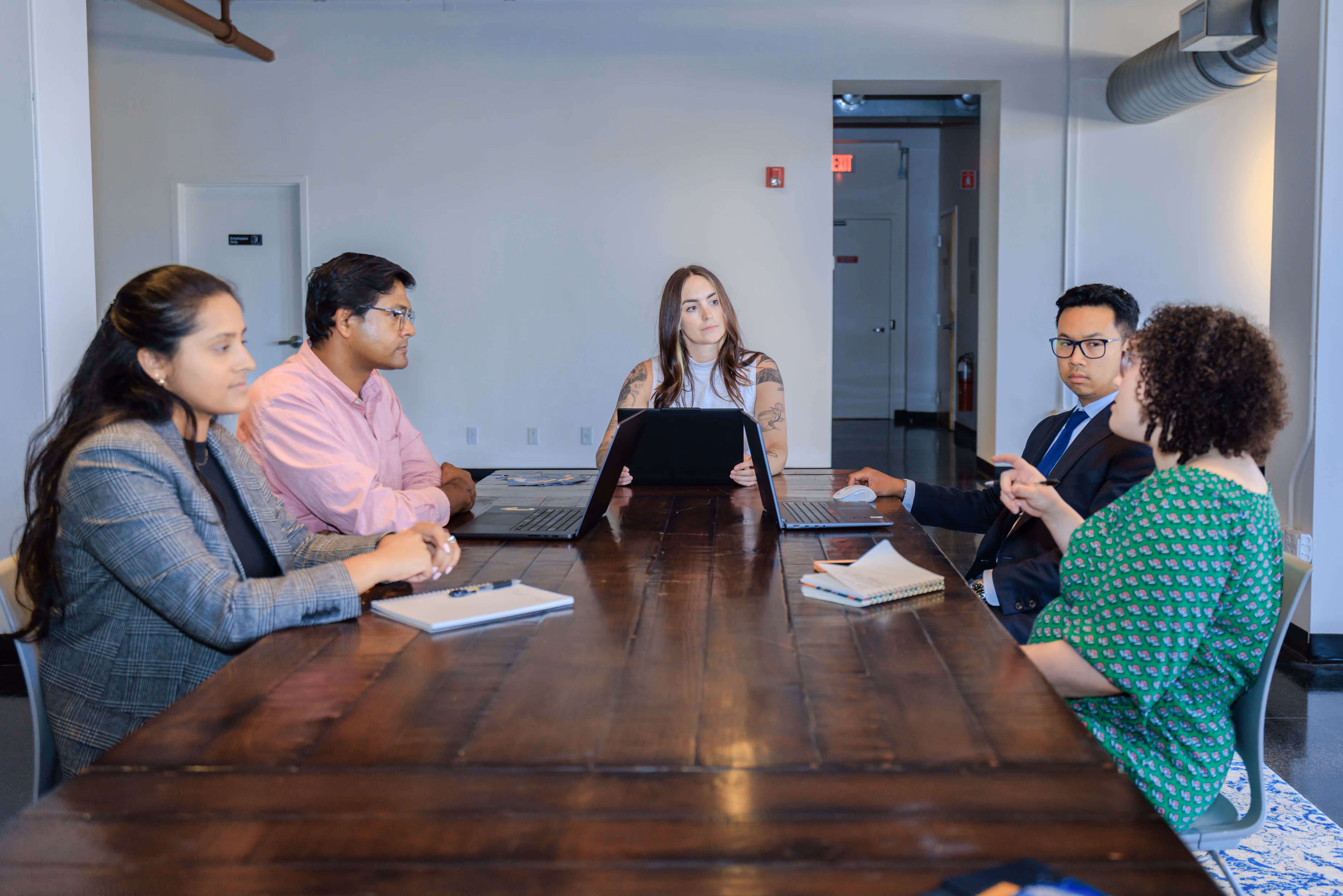 A group of people sitting around a wooden table.