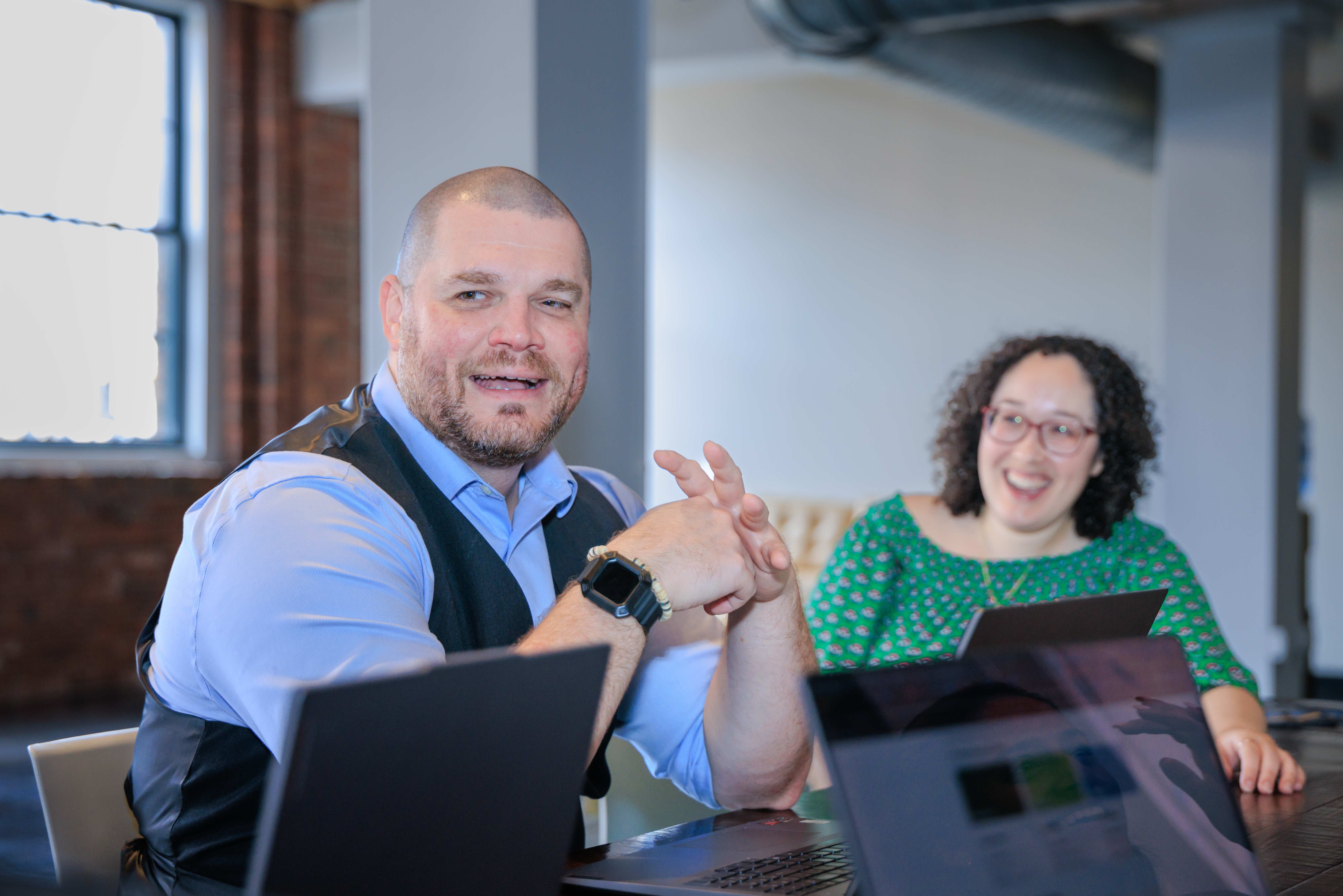 A man and a woman sitting at a table with laptops.