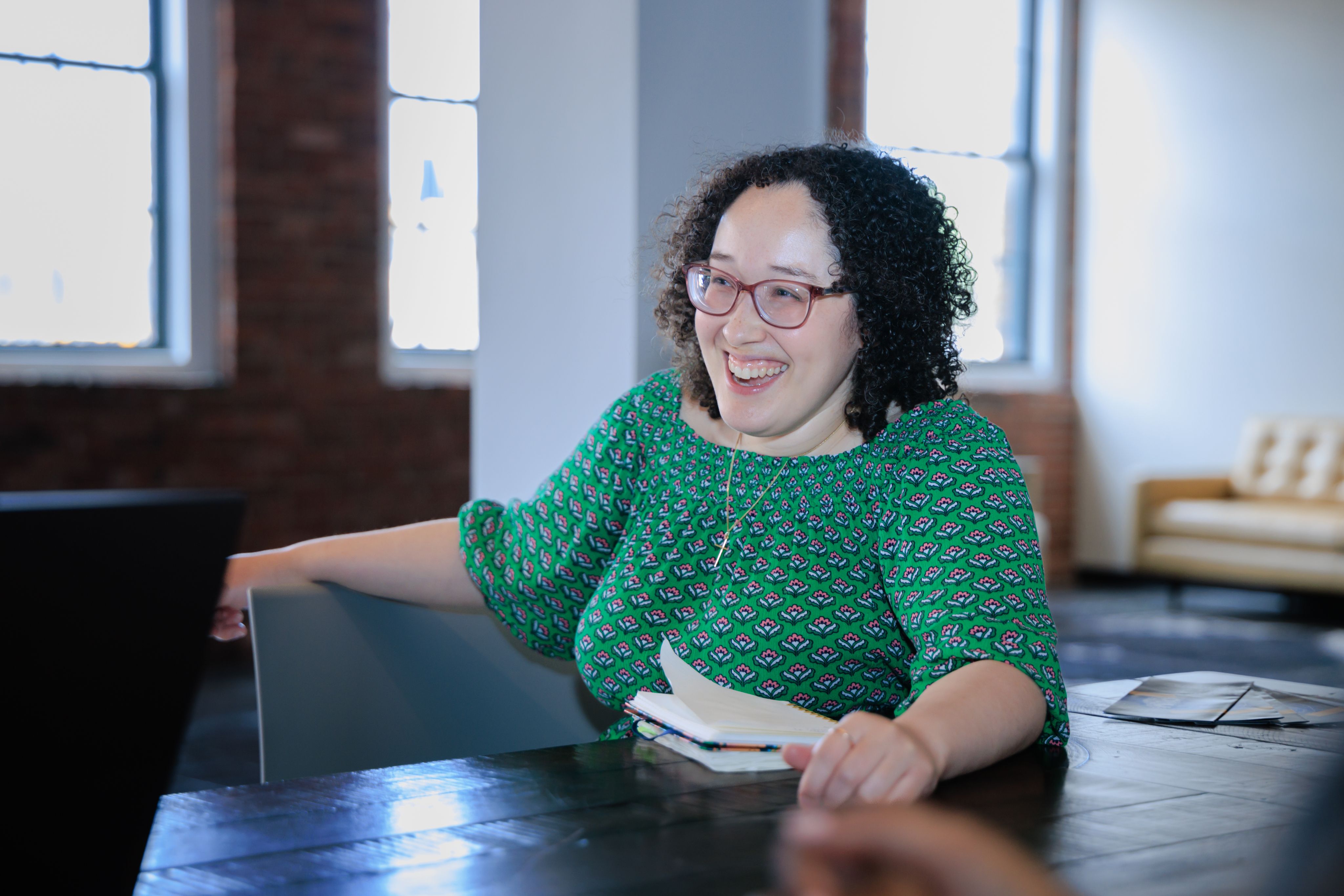 A woman sitting at a table in front of a laptop computer.