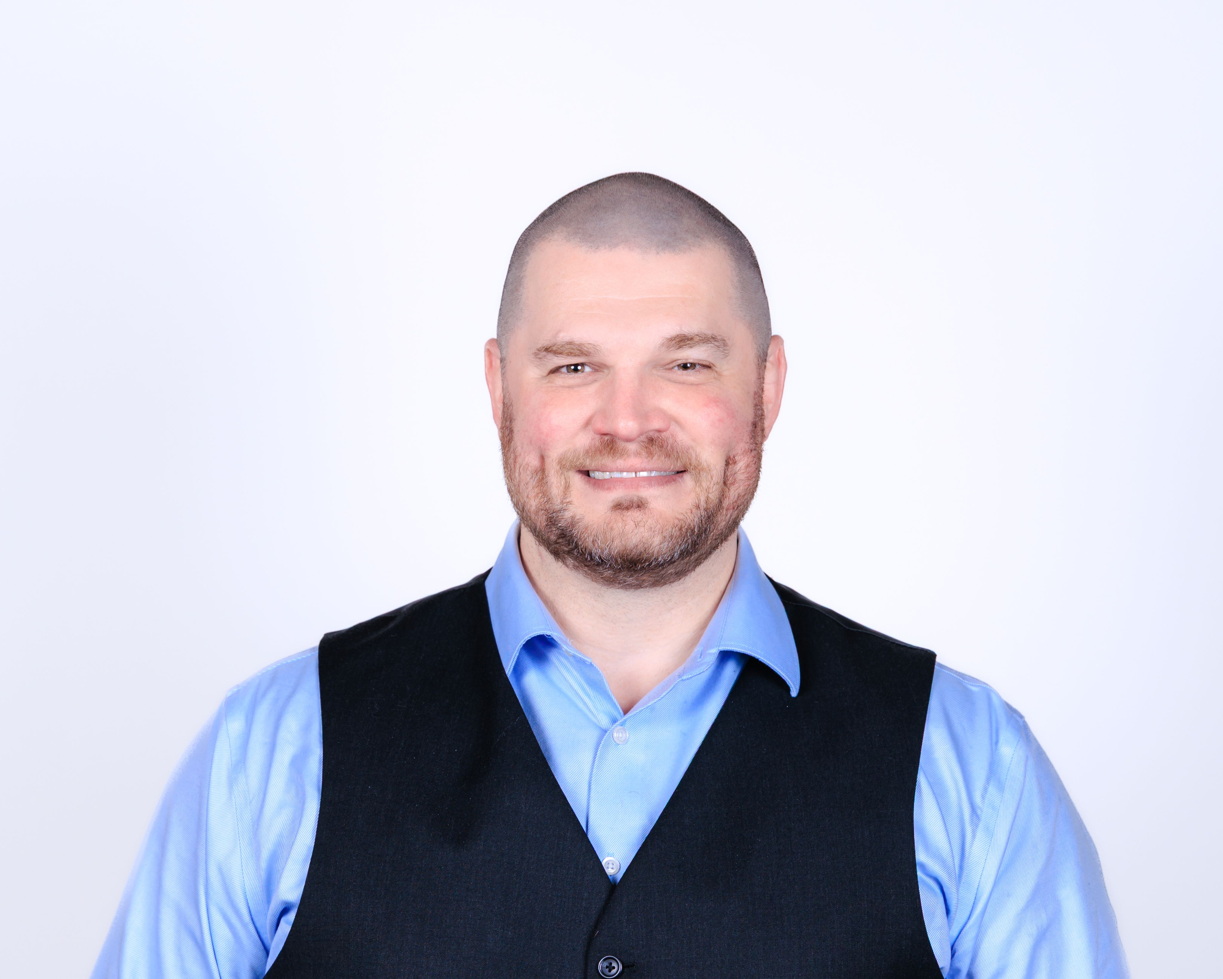 A man in a blue shirt and black vest.