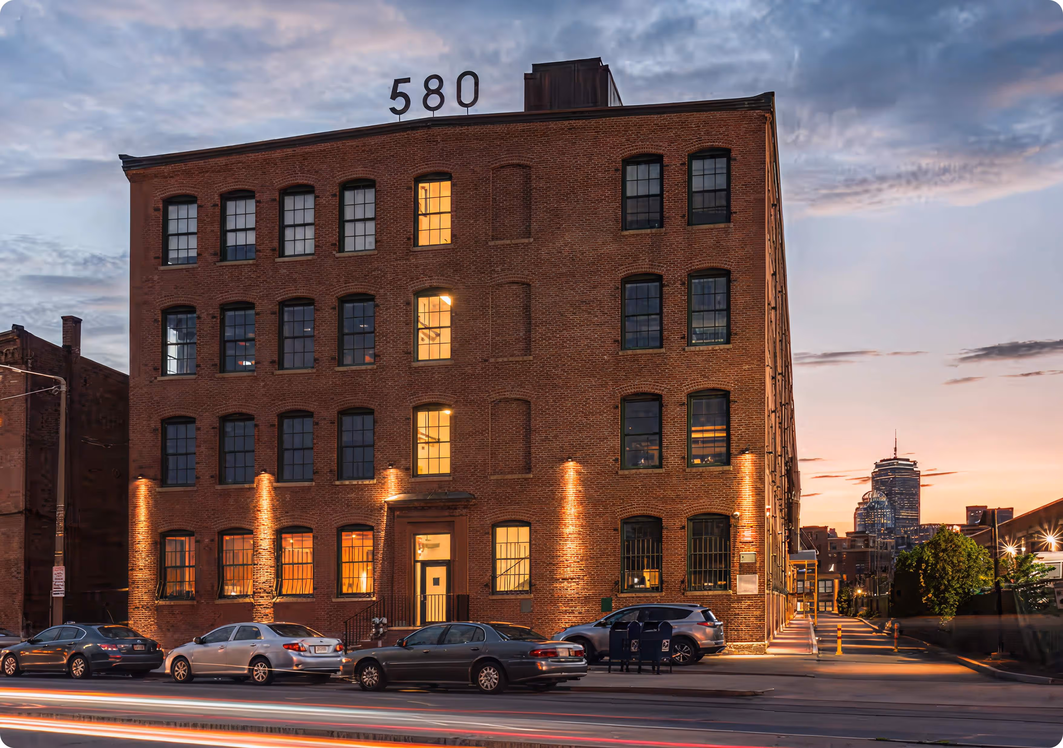 A tall brick building with cars parked in front of it.