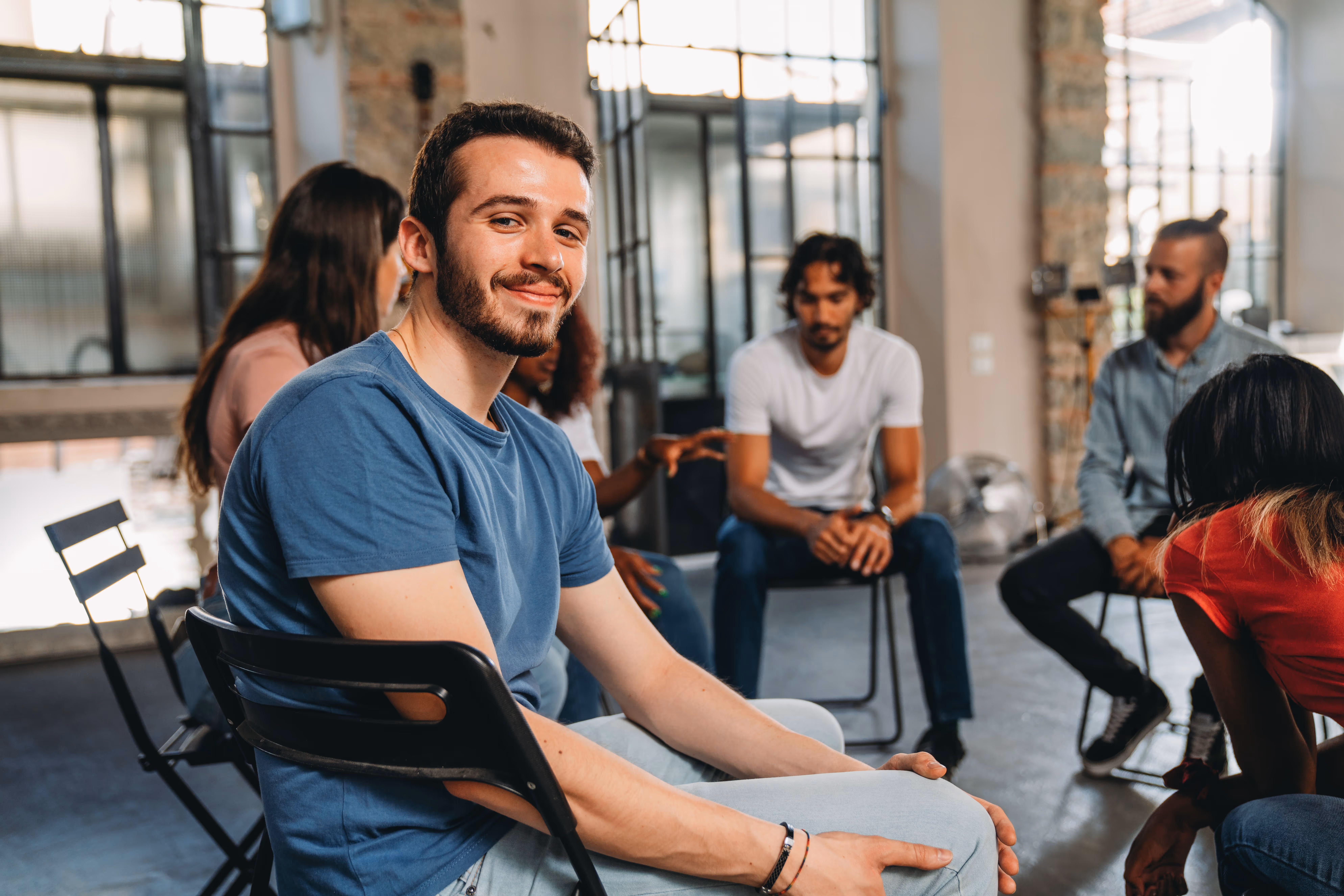 Smiling woman wearing headphones sitting cross-legged on a couch, video chatting on a laptop.