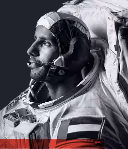 Black and white close-up of an astronaut in a space suit looking up and to the left.