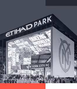 Crowd outside Etihad Park entrance with New York City FC logo and borough names displayed.