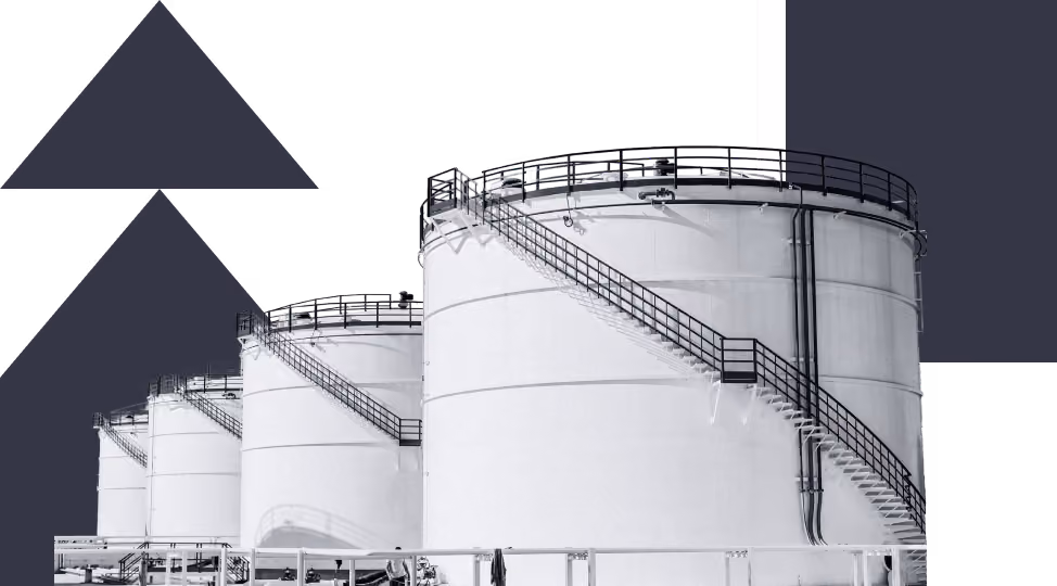 Large industrial storage tanks with spiral staircases and railings lined up in a row.