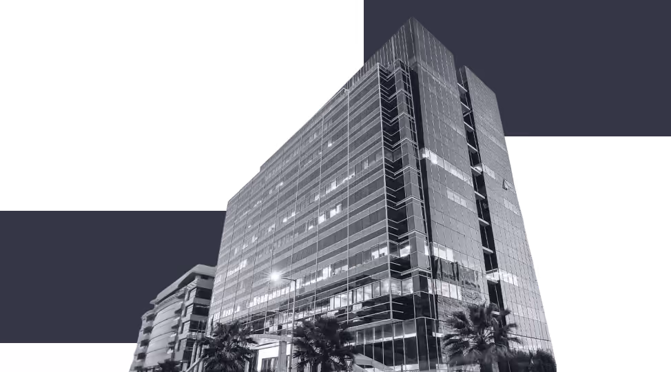 Low-angle view of a tall modern office building with glass windows and palm trees in front.