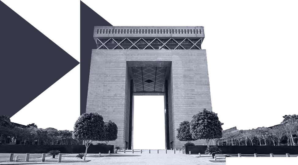 Large modern archway structure with trees and paved walkway in front under clear sky.
