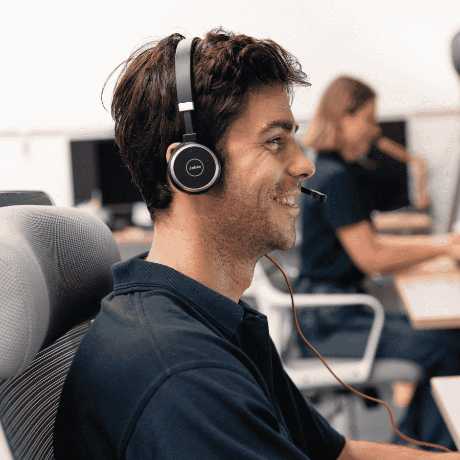 Customer support representative wearing Jabra headset smiling in office