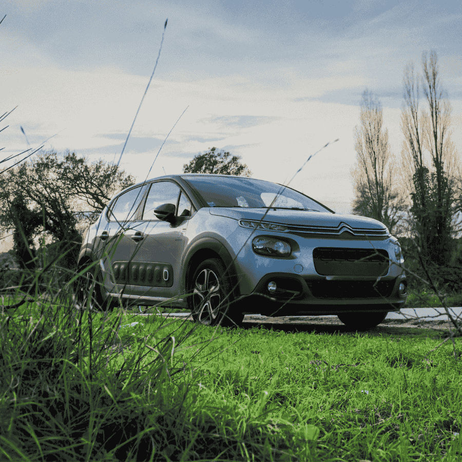 1800 Car Buyers employee smiling while checking tablet near car
