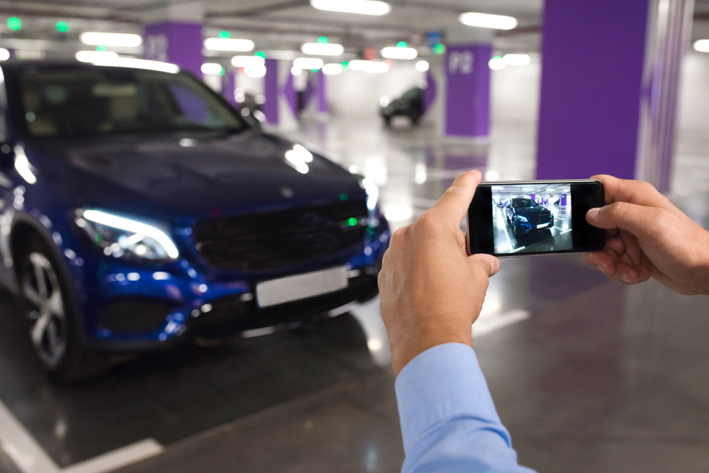 Person photographing a car with a smartphone to document its condition