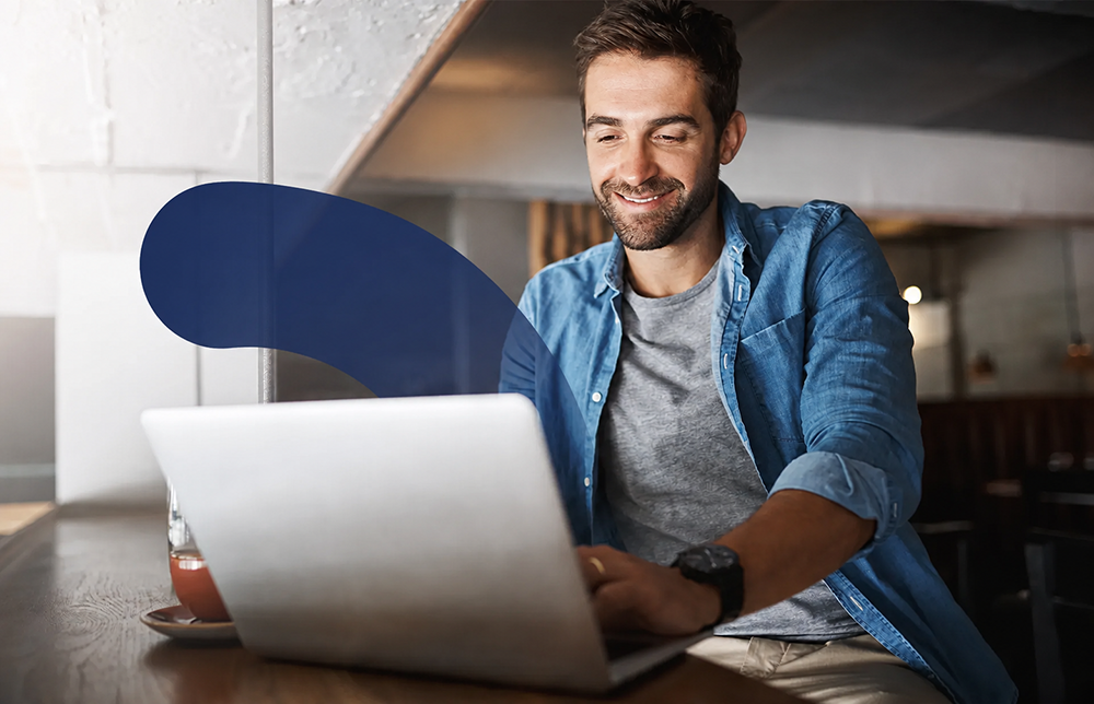 A smiling man uses a laptop at a table, with a graphic overlay showing a car valuation and search icon.