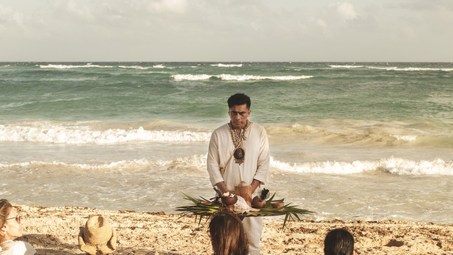 a man holding a tray of food on a beach