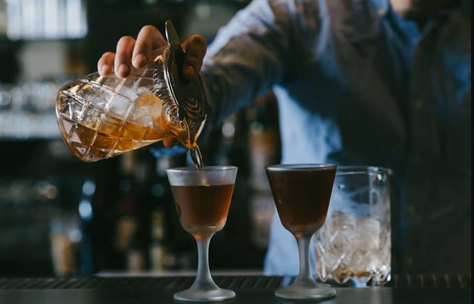 a person pouring a drink into a glass