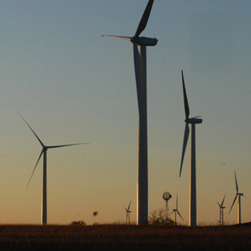 A wind farm is silhoutted against a prairie sunset