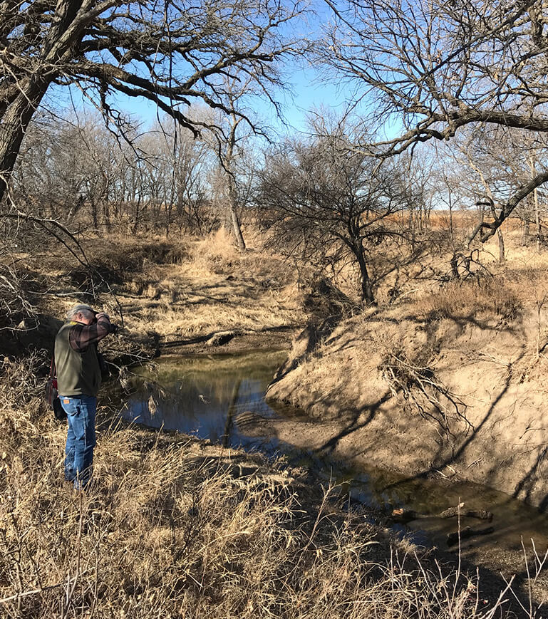 A photographer next to a meandering stream