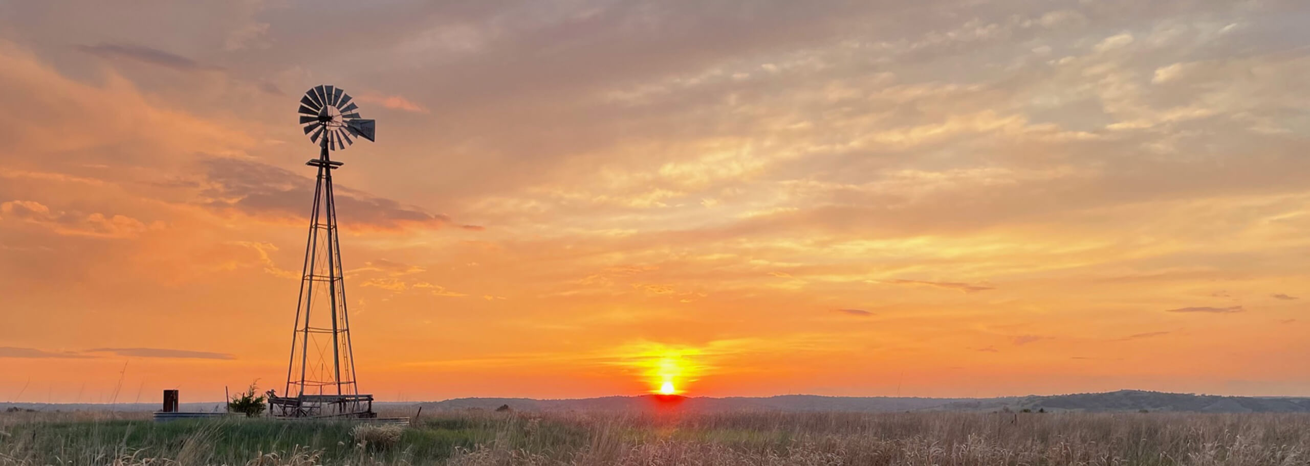 Silhouette of a windmill against a prairie sunset