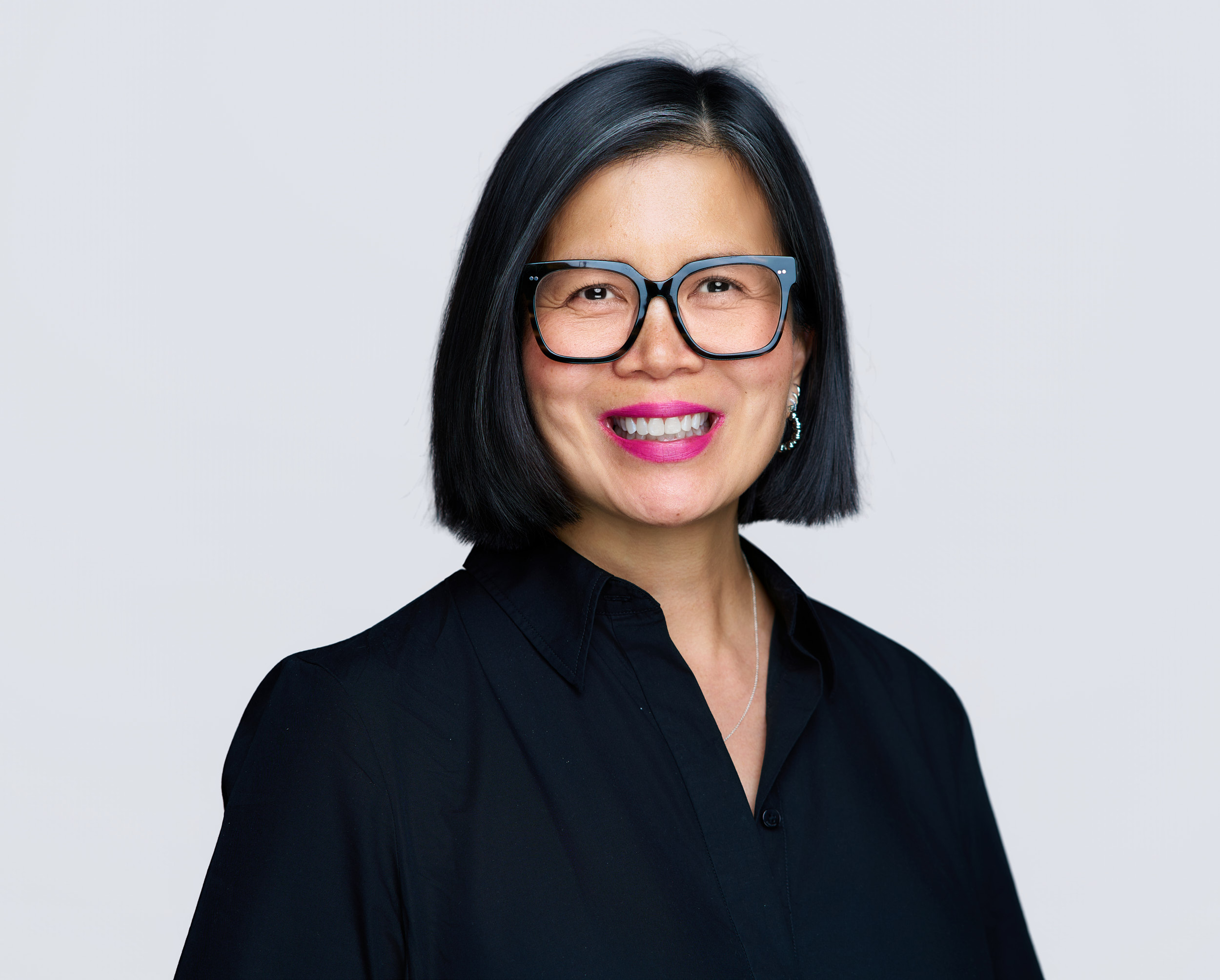 Business headshot of smiling woman with short black hair and glasses for Kimley-Horn. Created during an on-site corporate headshot session.