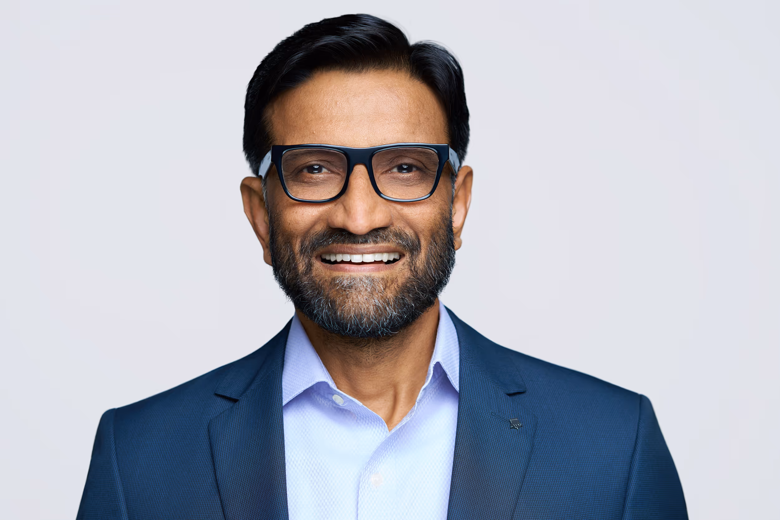 Professional corporate headshot of smiling man with glasses for Broadridge Financial. Part of a 346-headshot on-location corporate session, photographed over 2 days with 1 photographer.