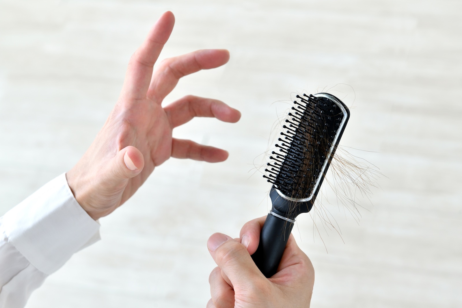 A man holding a hairbrush full of fallen hair