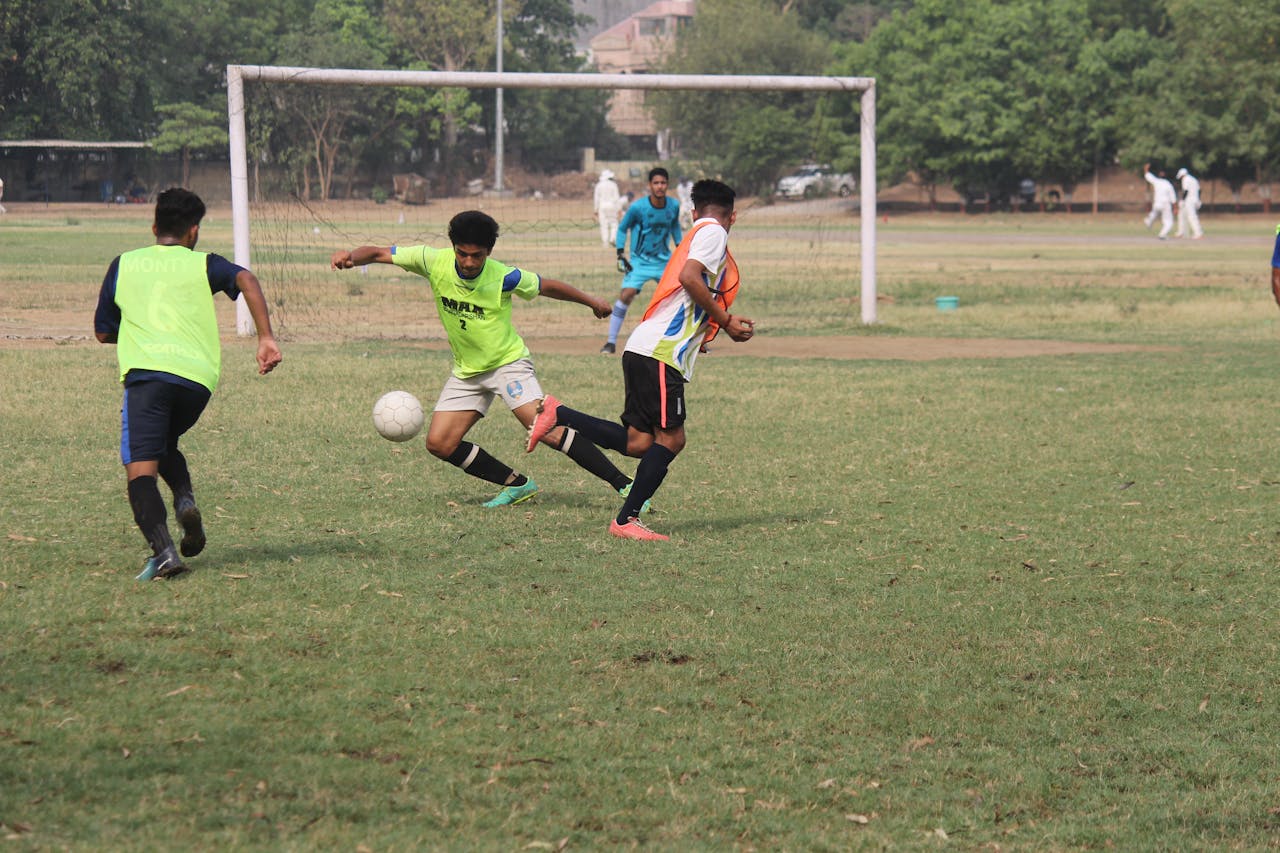 Players in neon vests competing for ball possession on a grass soccer field
