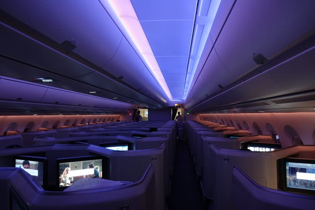 an inside of an airplane with rows of seats and a television